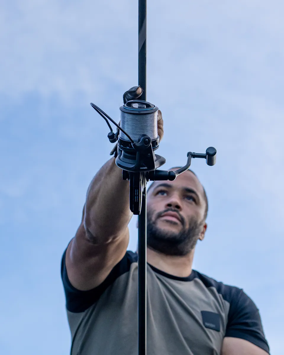 Low-angle portrait of Jermaine with his hand on the reel against a blue sky
