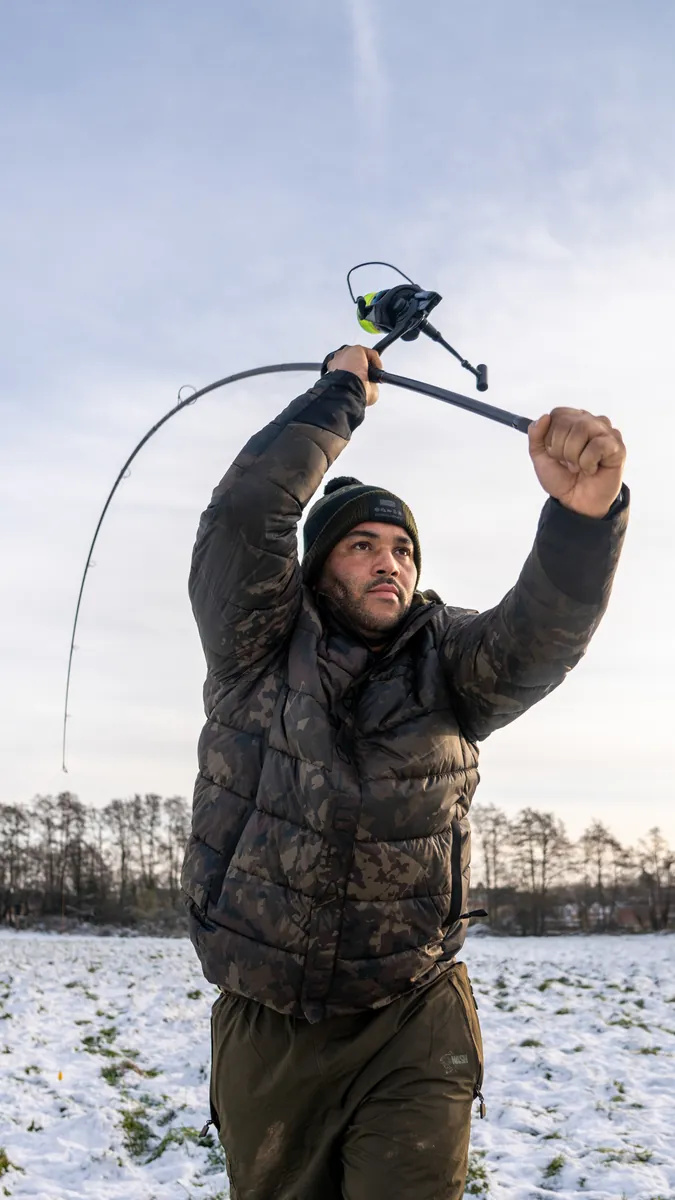 Jermaine in an overhead casting stance in a snowy field